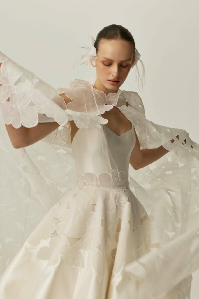 Woman in white gown poses with sheer fabric.