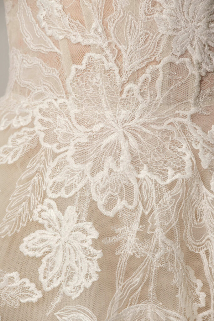 White floral lace embroidery on sheer beige fabric.