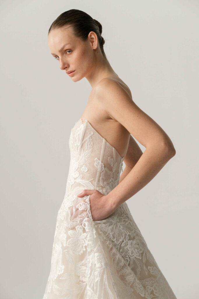 Woman in white lace gown, hair in bun.