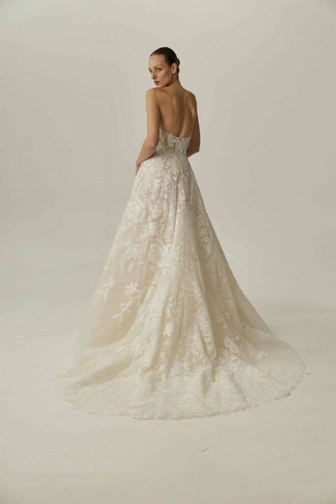 Woman in strapless lace wedding gown looks back.