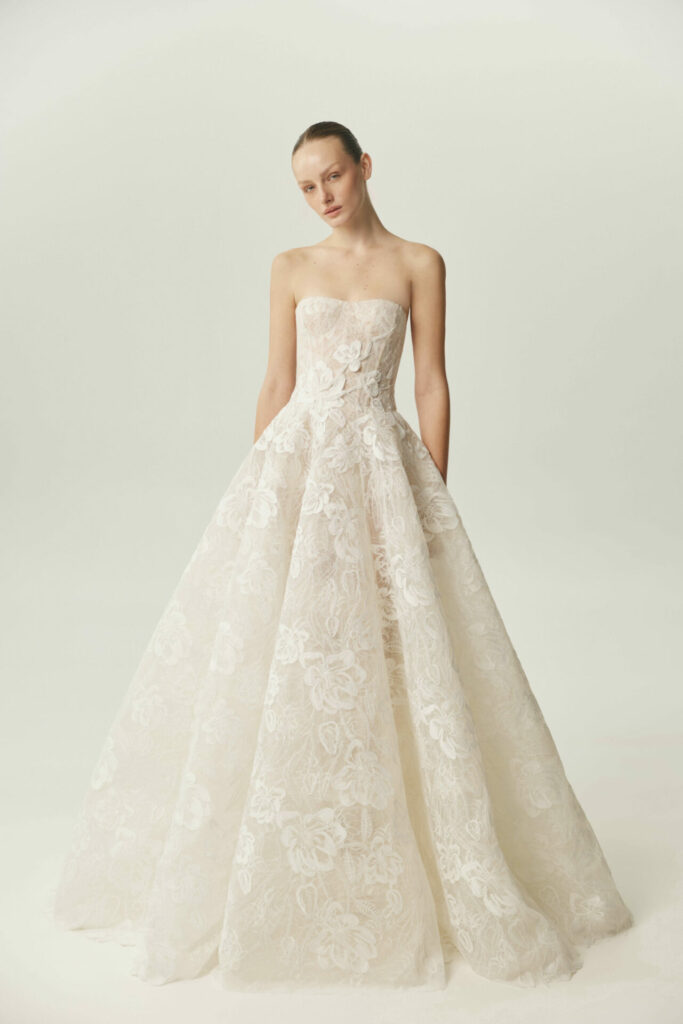 Woman in strapless white gown stands, glancing sideways.