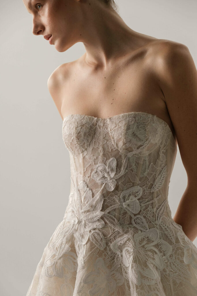 Woman in strapless lace wedding dress, floral detail.