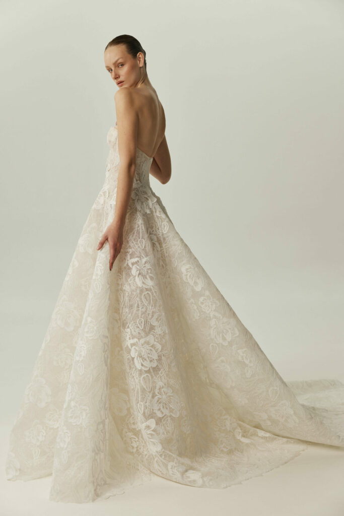 Woman in strapless ivory lace gown with train.