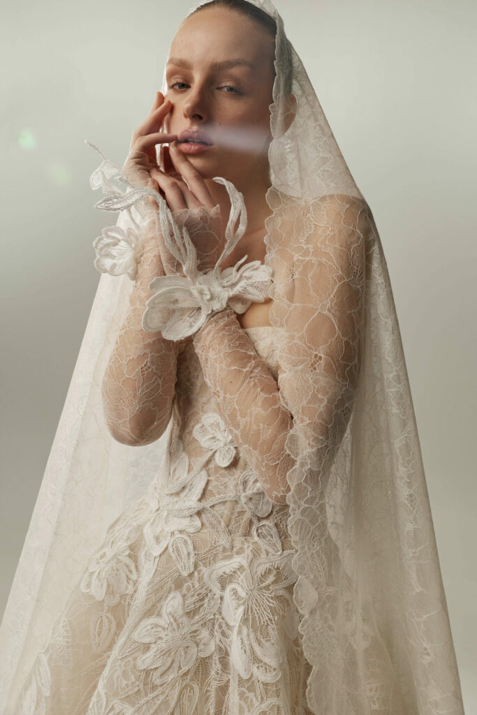 Person in lace wedding gown softly touching face.