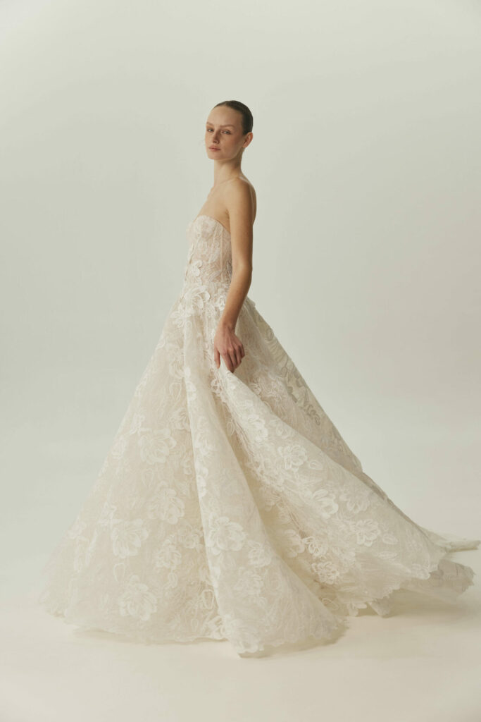 Woman in strapless lace gown glances back.