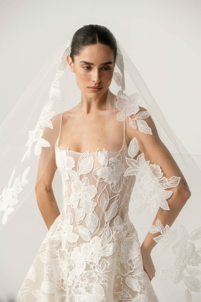 Bride in lace dress and veil, serene expression.