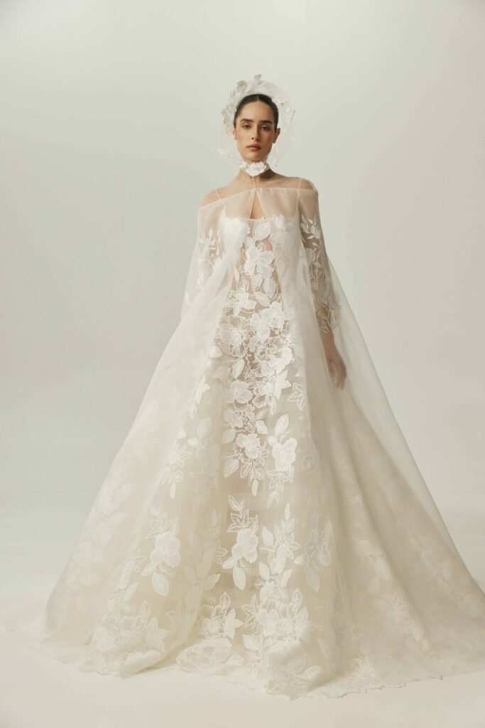 Woman in sheer white lace wedding gown and cape.