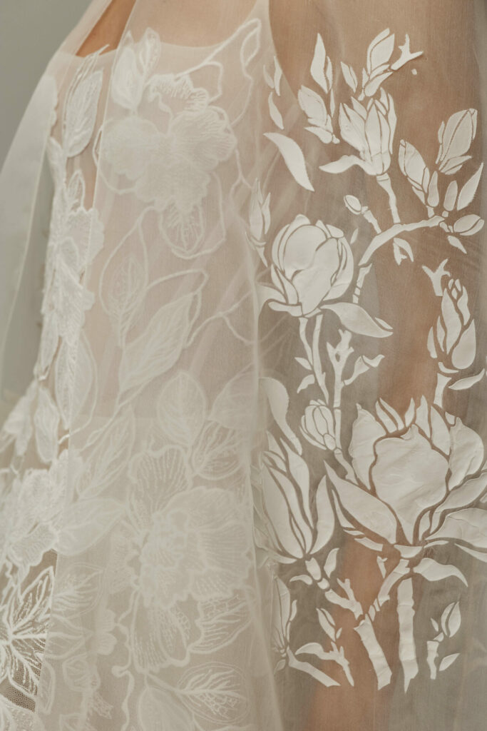 Sheer white floral-embroidered fabric on shoulder and arm.