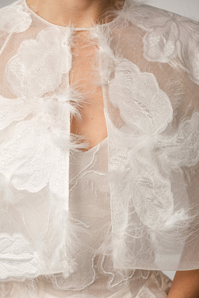 Sheer white Clea wedding dress with floral, feather details.