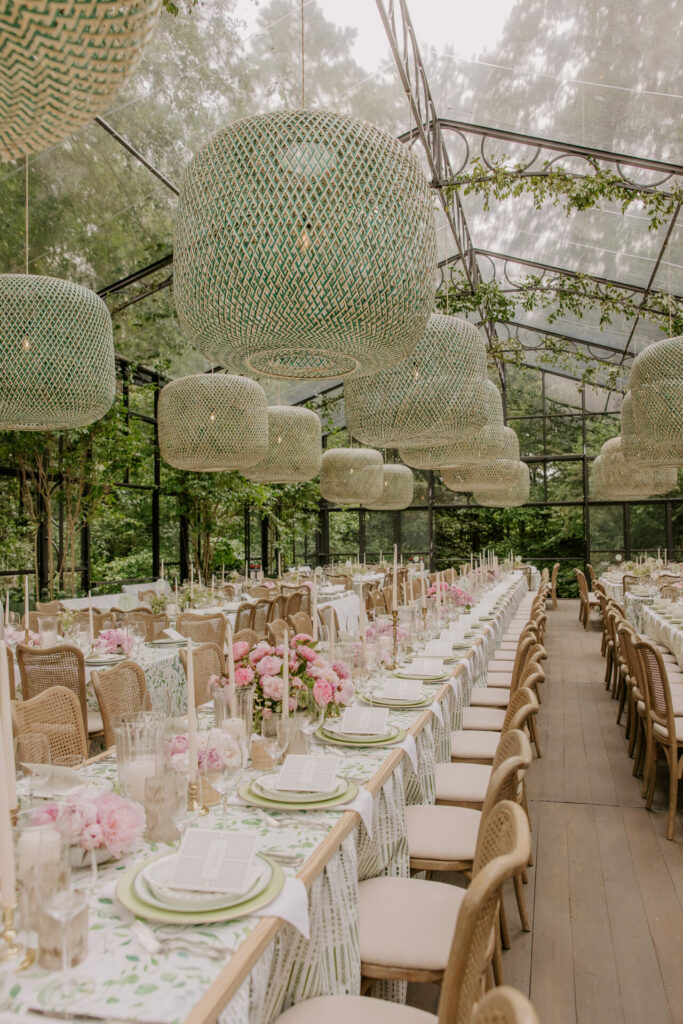 Chic outdoor dining with floral tables, lights, greenery.