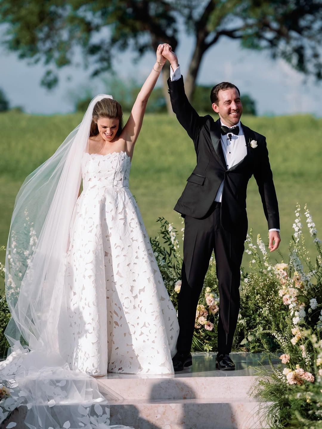 Bride and groom outdoors, holding hands and smiling.