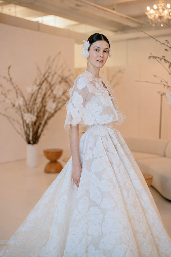 Bride in floral Clea gown poses in elegant room.
