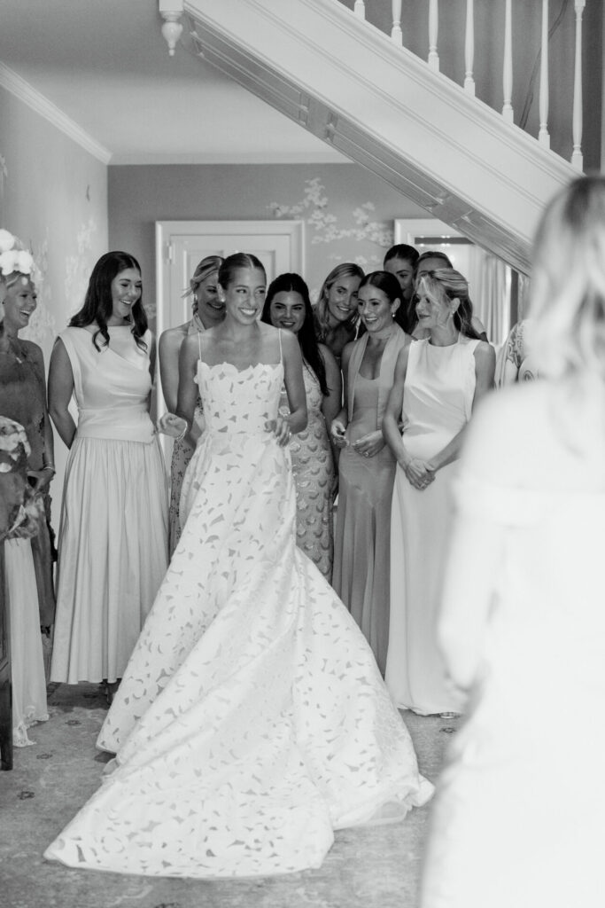 Bride Katya Ruiz and bridesmaids smiling in luxurious, patterned gowns, black-and-white staircase bridal couture moment.
