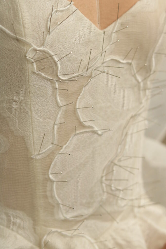 Cream fabric pinned on dress form, tailoring in progress.