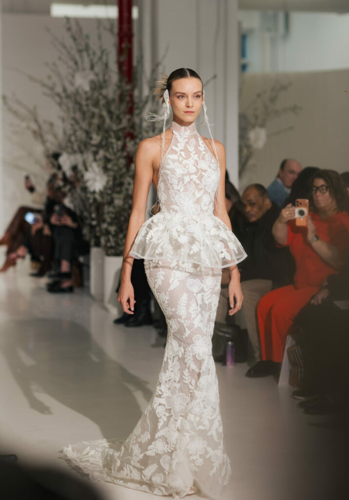 Model in floral lace Clea wedding dress on runway.