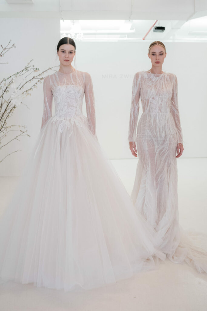 Two models in white lace gowns, minimal background.