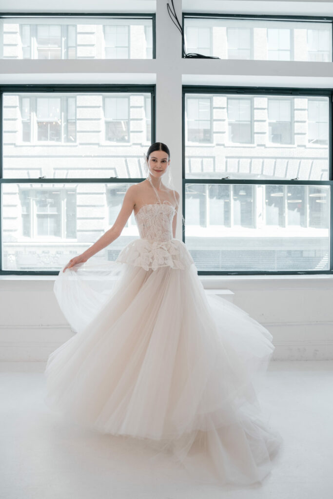 Woman in strapless white wedding dress near bright windows.