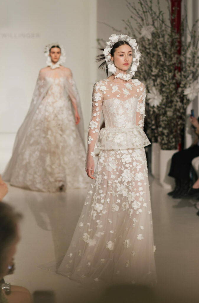 Mira Zwillinger SS2027 brides in sheer floral lace bridal gowns with detachable basque tops on runway.