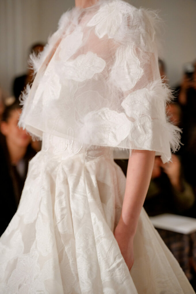 Model in textured Clea wedding dress, floral sheer cape.