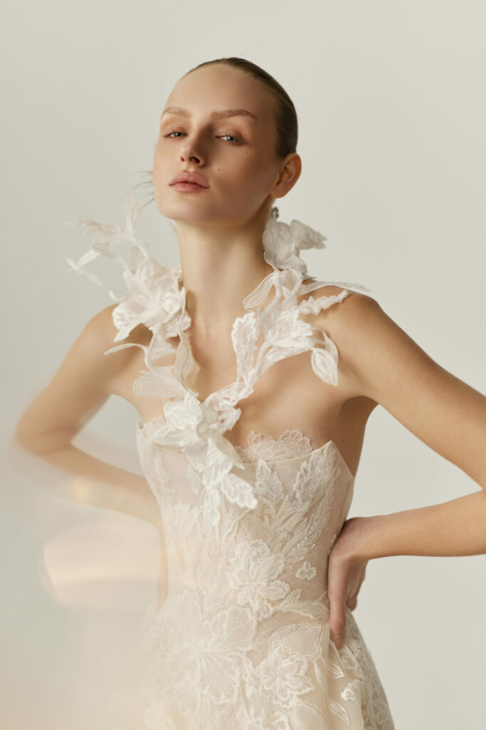 Woman in sheer lace Clea wedding dress posing.