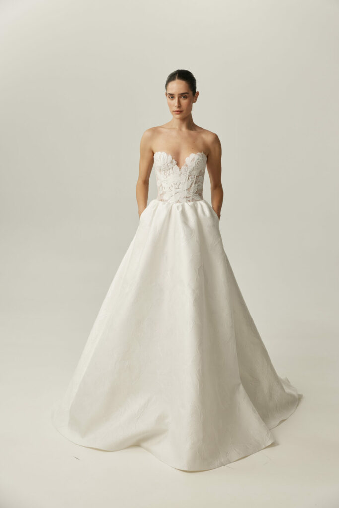 Woman in strapless Clea wedding dress, hands in pockets.