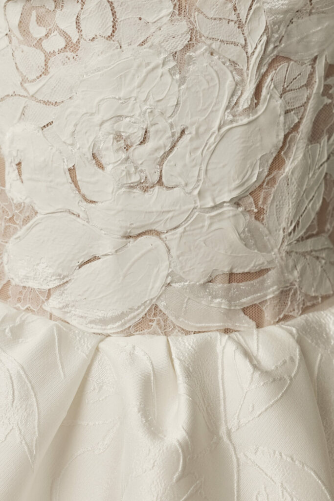 White lace fabric with raised floral embroidery.