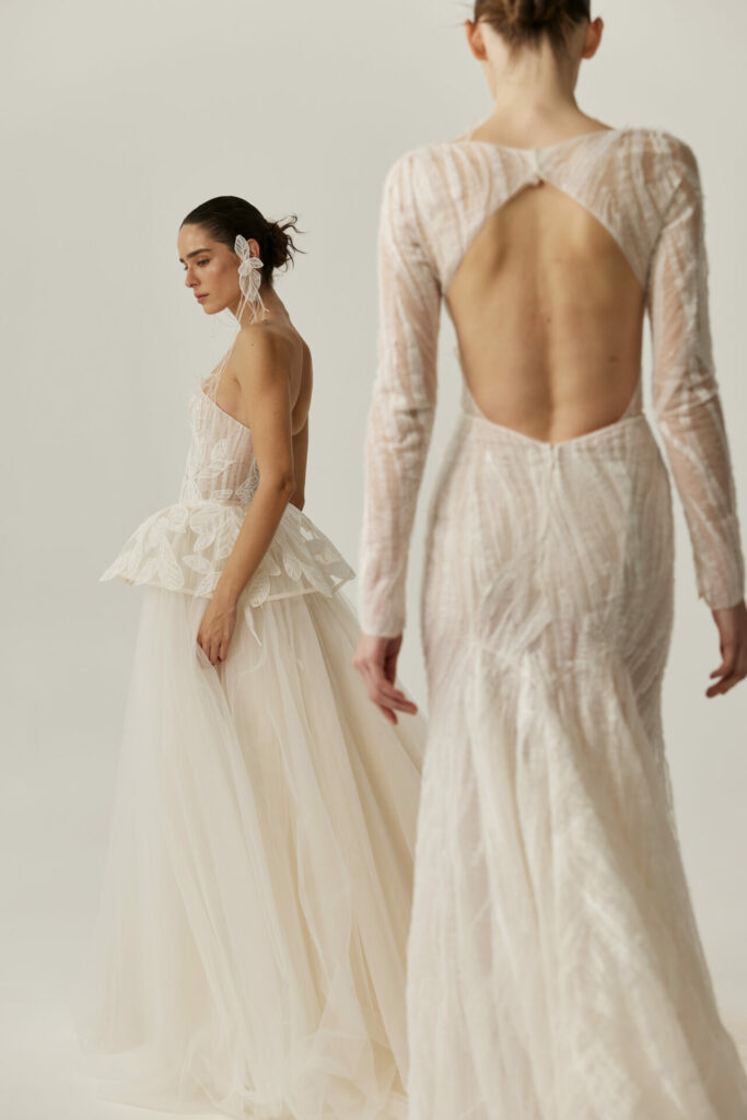 Two women in white bridal gowns pose together.
