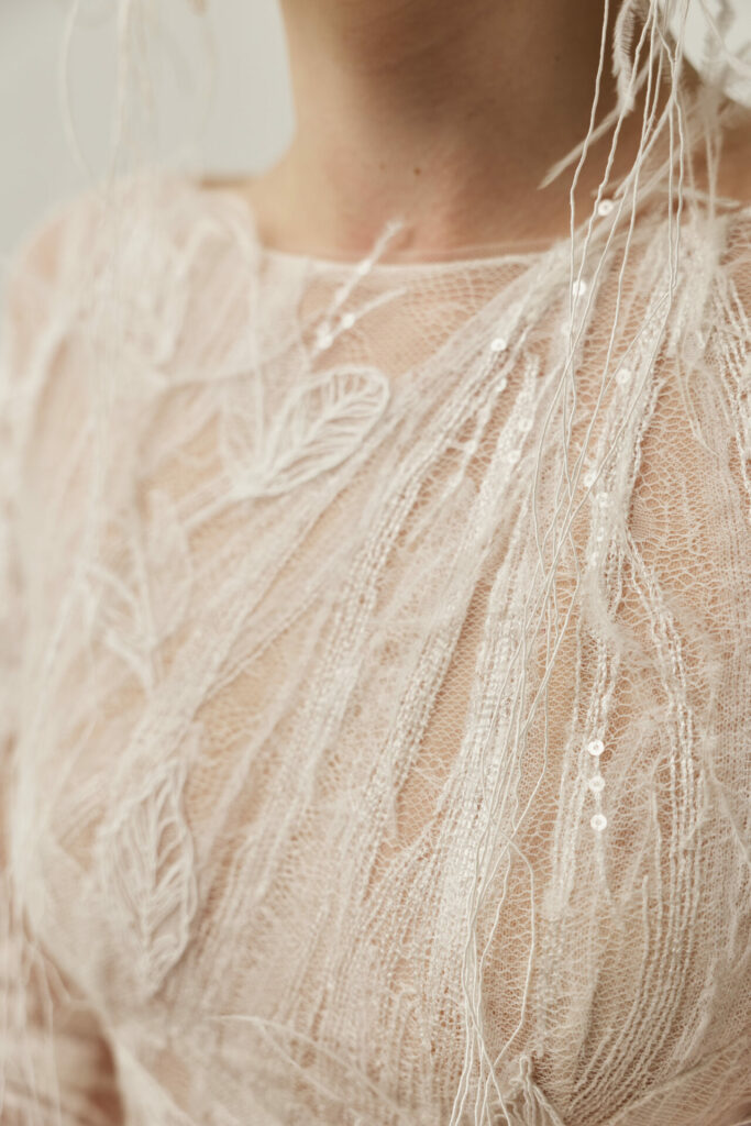 Sheer embroidered fabric with sequins and leaf patterns.