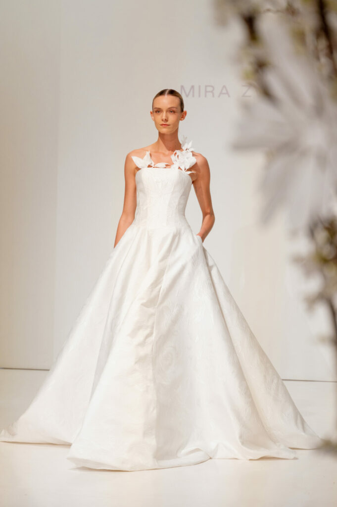 Model in white strapless wedding dress with flowers.
