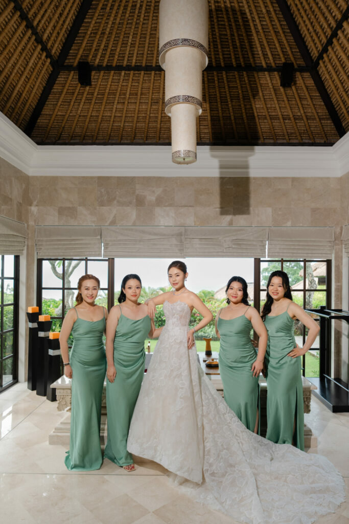 Bride with four bridesmaids in elegant, sunlit room.