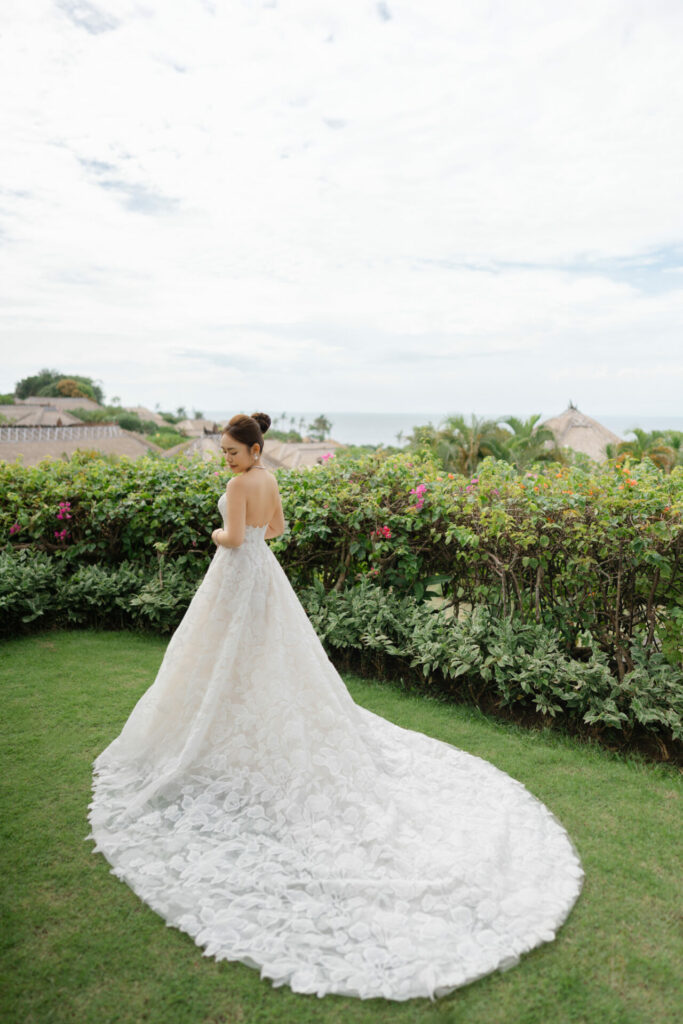 Katya Ruiz in white strapless gown by garden.