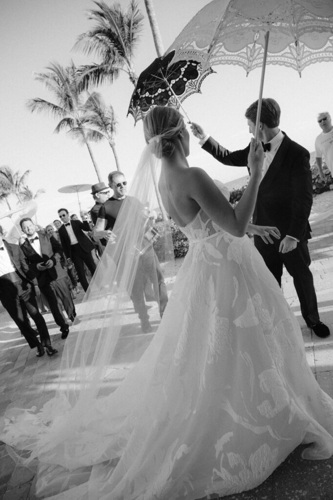 Bride and groom outdoors, guests watch, elegant wedding.
