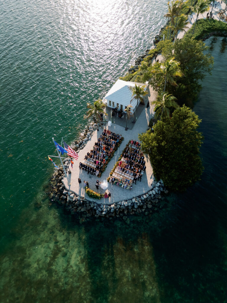 Aerial view: waterfront wedding, palm peninsula, elegant bride.