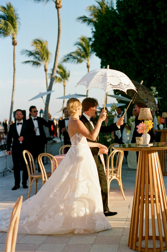 Bride and groom under black lace parasol, elegant wedding.