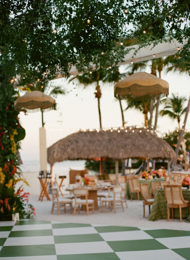 Beachside luxury wedding with checkered dance floor, tropical decor.