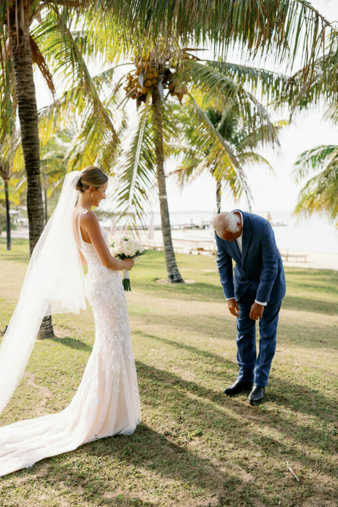 Bride in Clea dress, emotional man under palm trees.