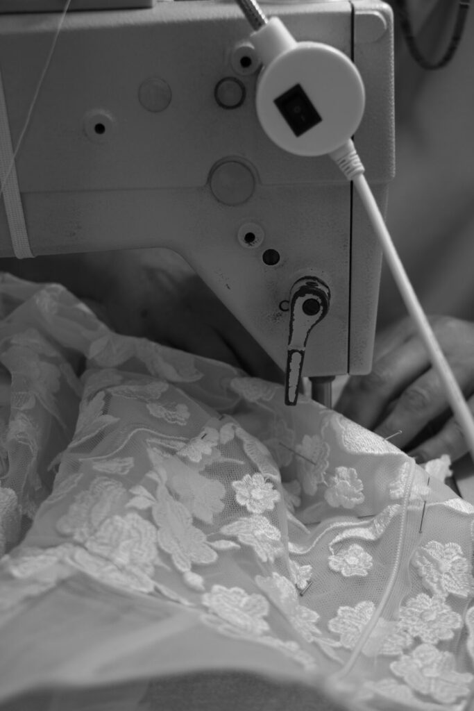 Hand guides lace under Ness & Nessia sewing machine.