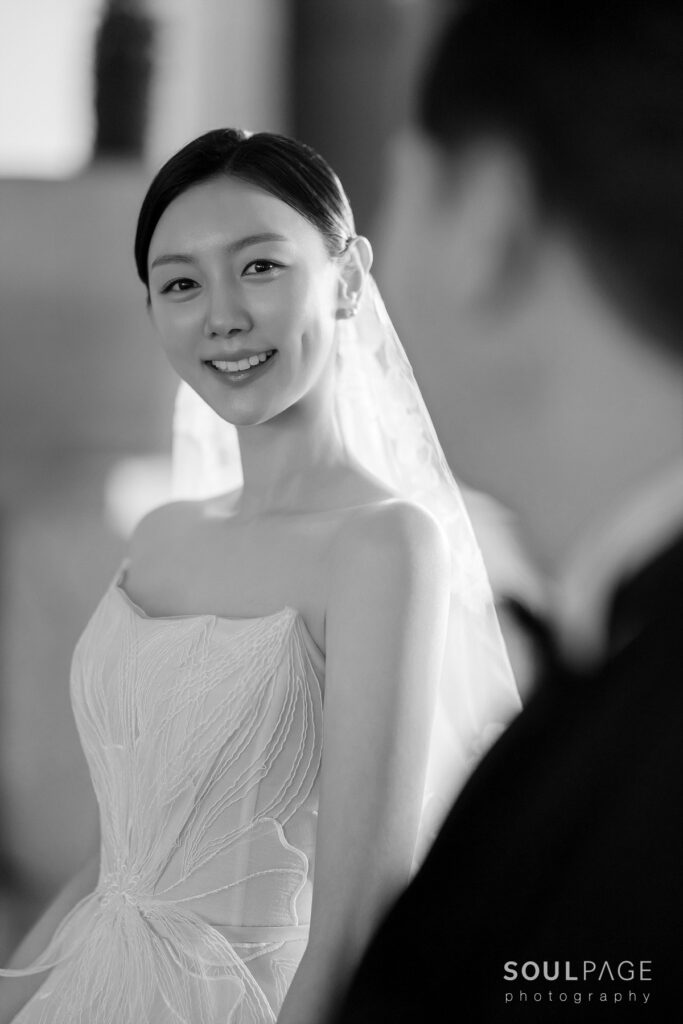 Smiling bride in strapless dress, black-and-white photo.