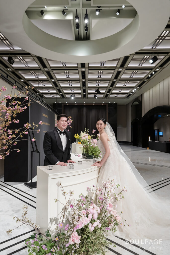 Smiling bride and groom at floral-decorated table indoors.