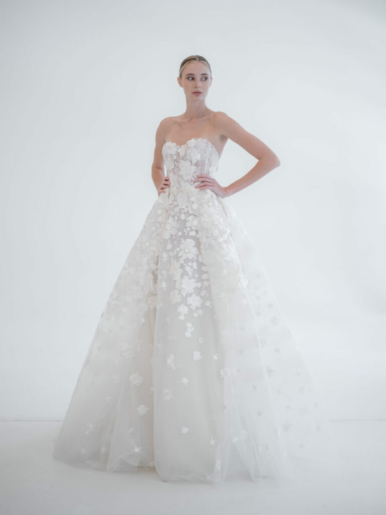 Confident woman in floral strapless gown, white background.