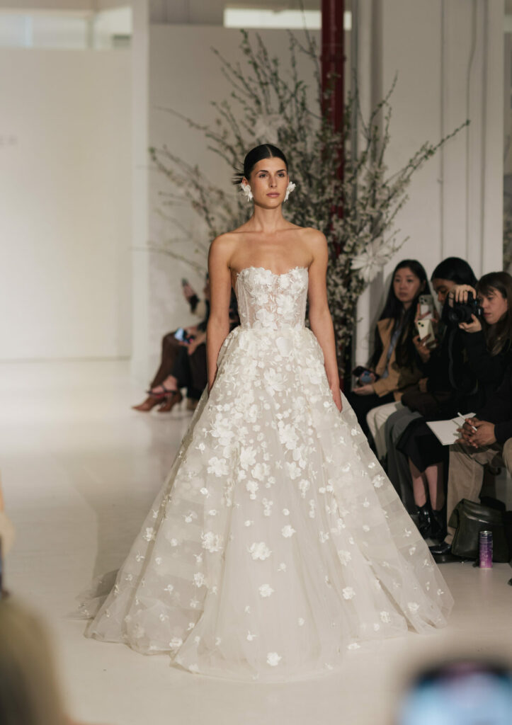 Model in floral strapless wedding gown on runway.