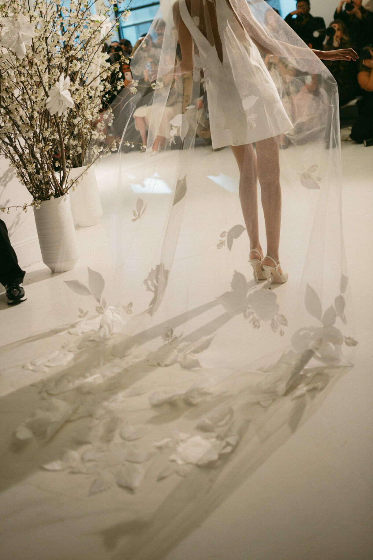 Bride in short dress, floral veil, bright room.