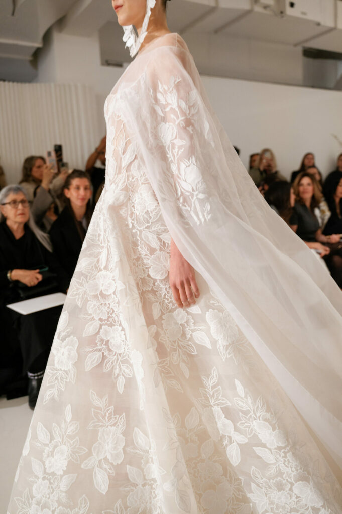 Model in sheer embroidered gown on runway.