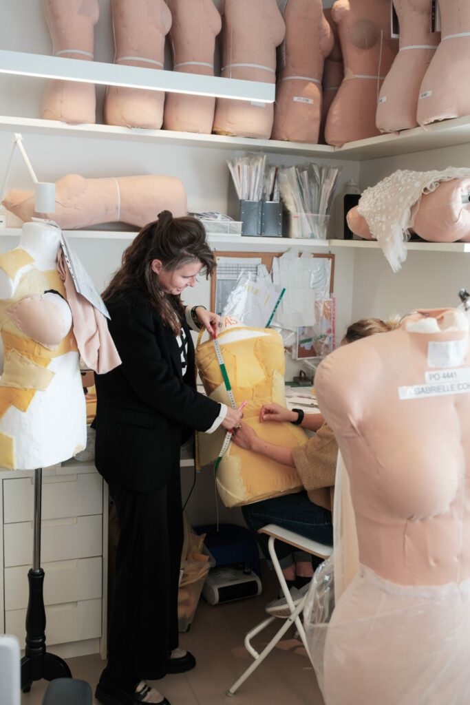 Two people measure and pin fabric in sewing studio.
