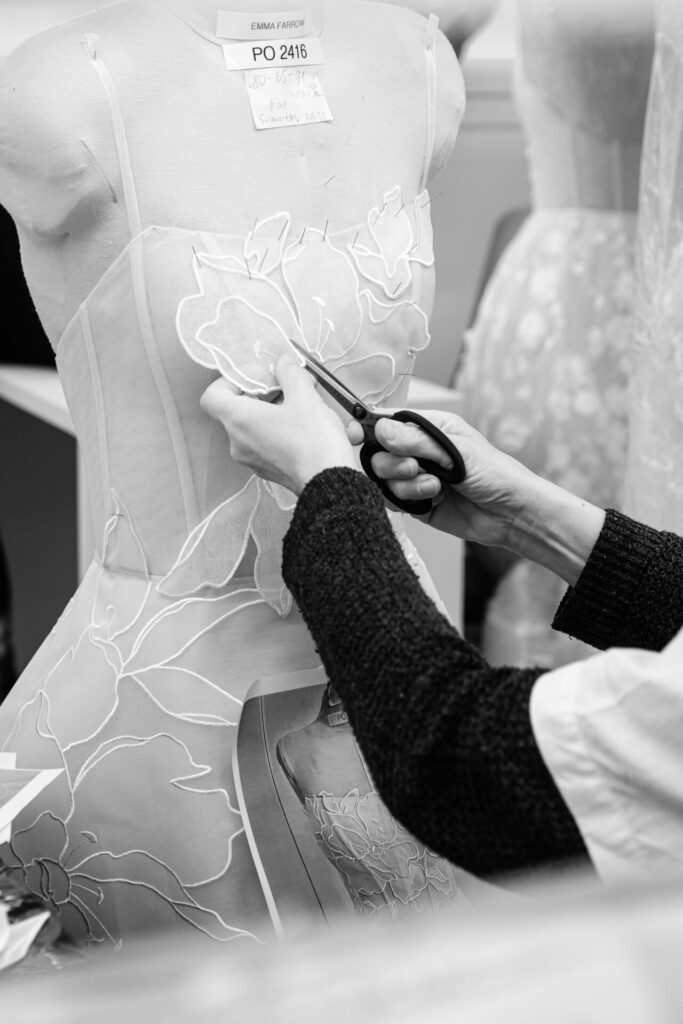 Black-and-white: person cuts intricate floral lace dress.