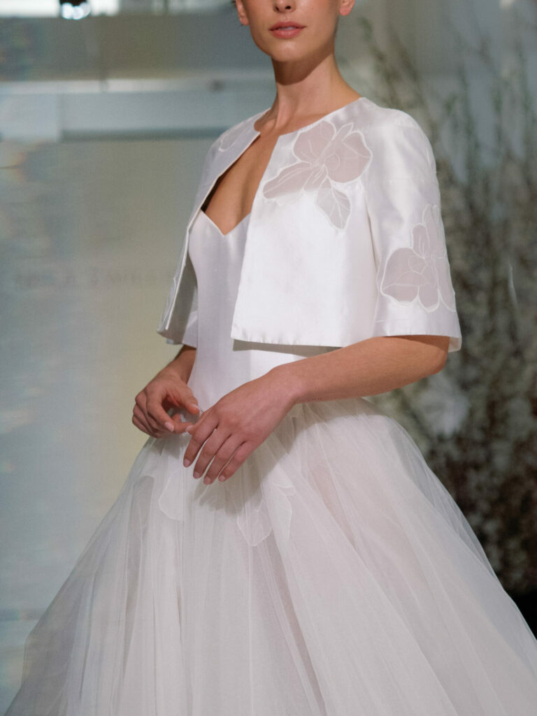 Model in Clea strapless tulle gown, floral jacket.