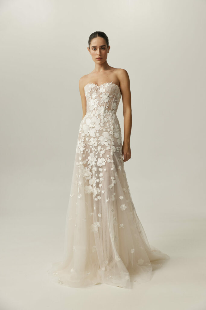 Woman in strapless floral wedding gown, light background.