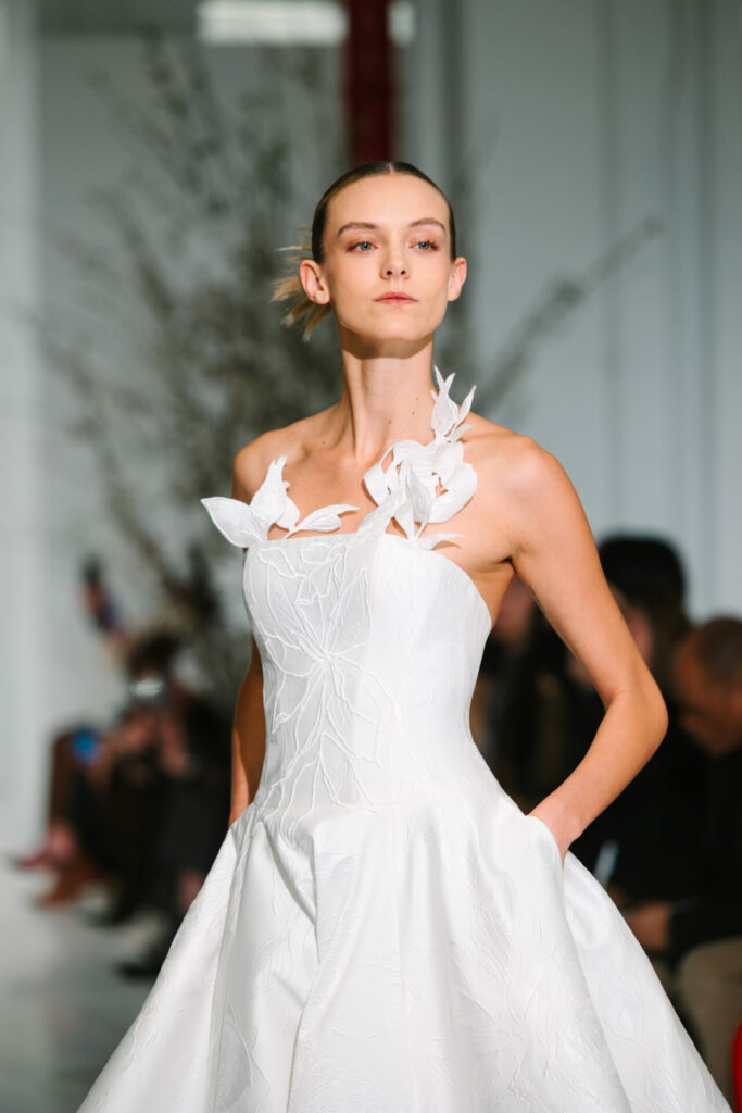Model in white strapless Clea wedding dress on runway.