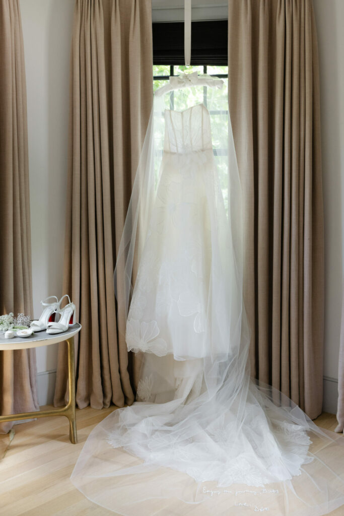 Wedding dress and veil by window, shoes nearby.