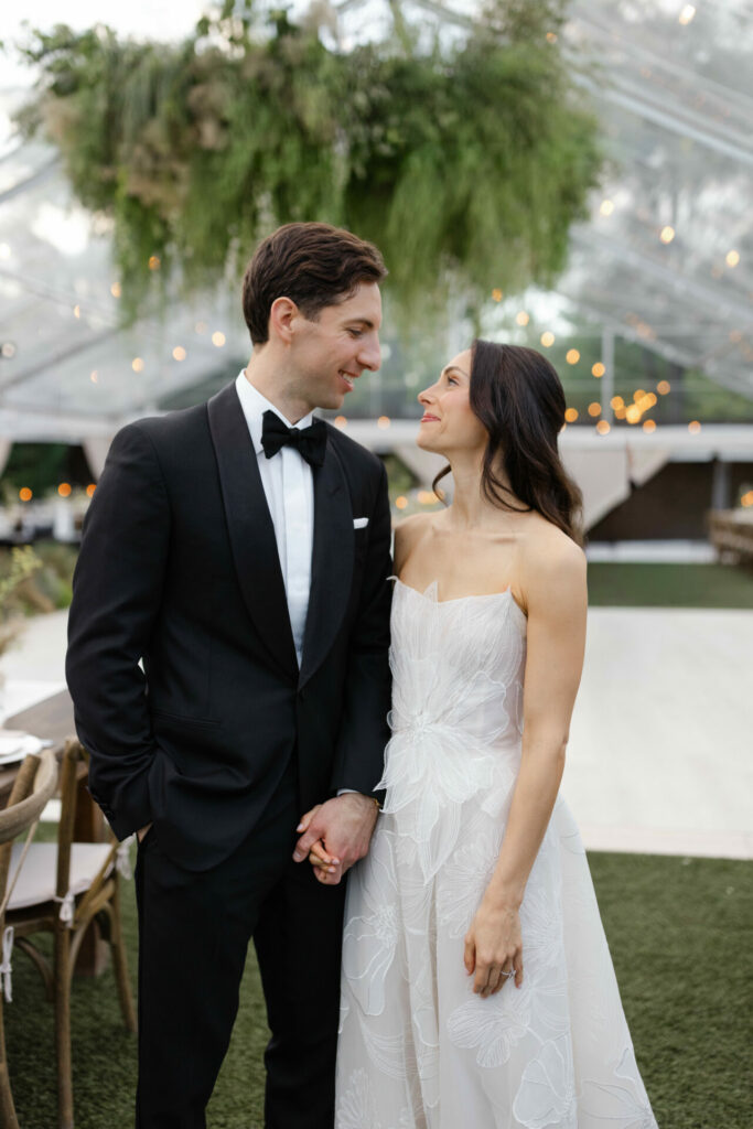 Bride and groom smiling under a canopy with lights.
